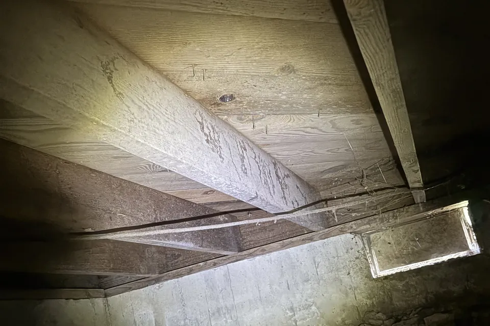 Original inspection photo of wooden floor framing in a crawlspace