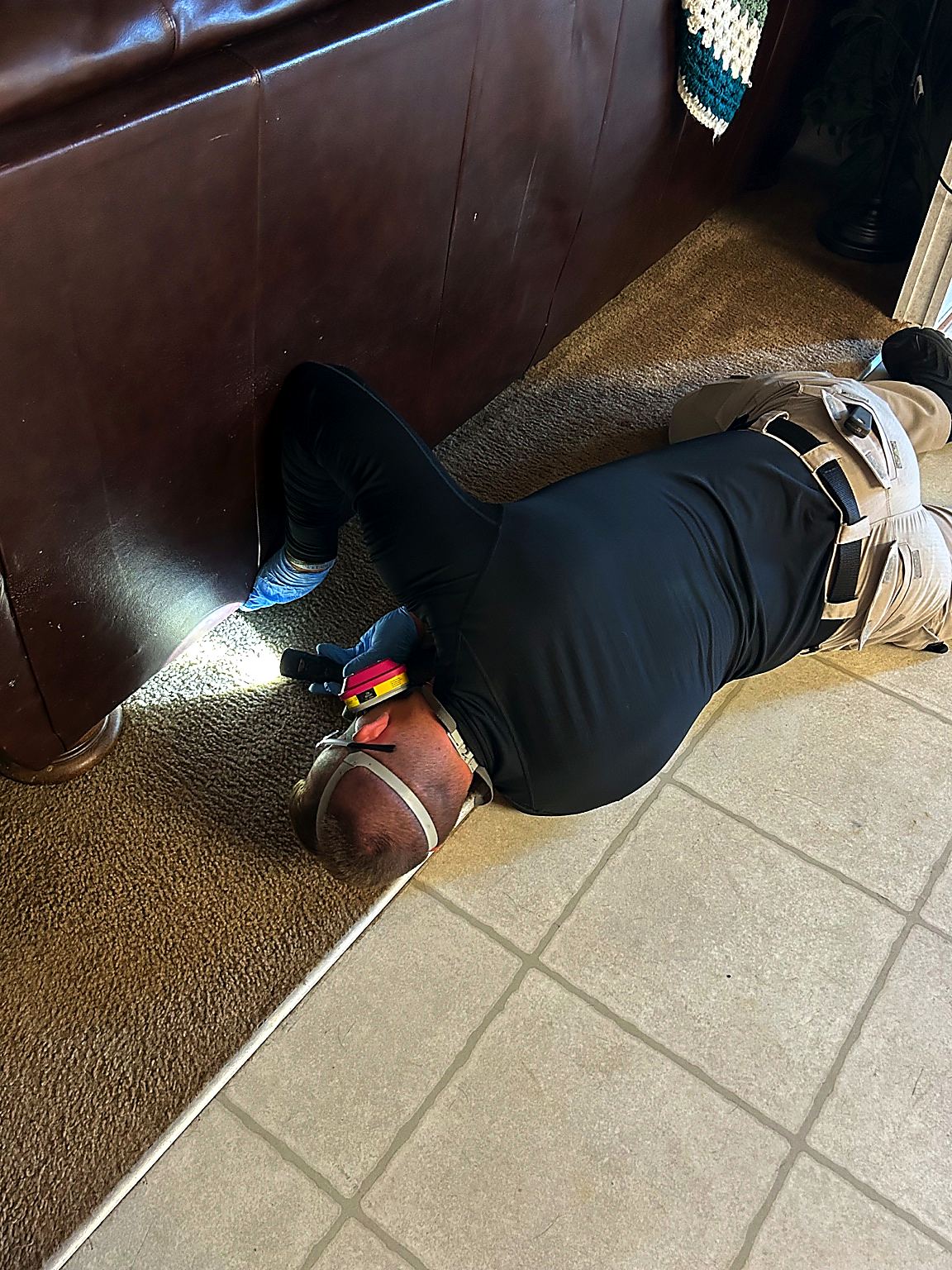 Bret inspecting under a sofa during a bed bug inspection