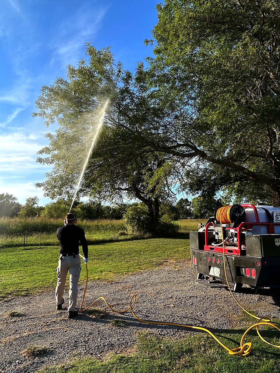 Bret spraying trees and lawn areas for outdoor pests