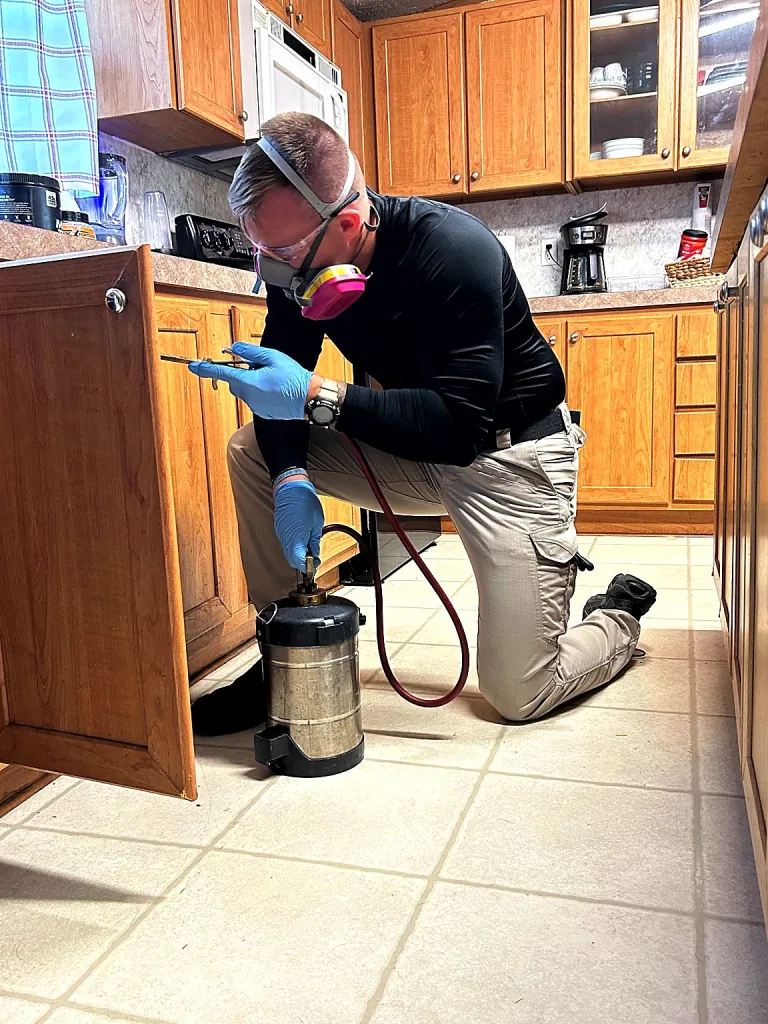 Bret Elza treating kitchen cabinets for pests in an Oklahoma home